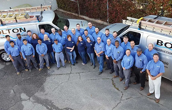 Members of the Bolton Construction Services team standing by a couple of their service vans